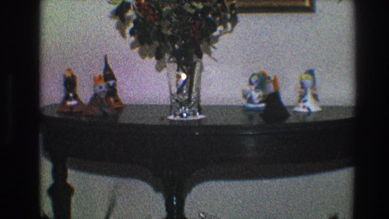 Dark console table with a vase of greenery and small figurines against a pale wall.