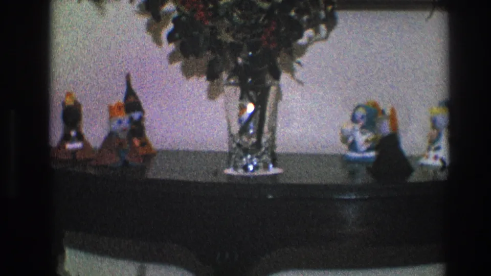 1968 Toledo home interior frame with a dark console table, glass vase, greenery, and decorative figurines near a pale wall.