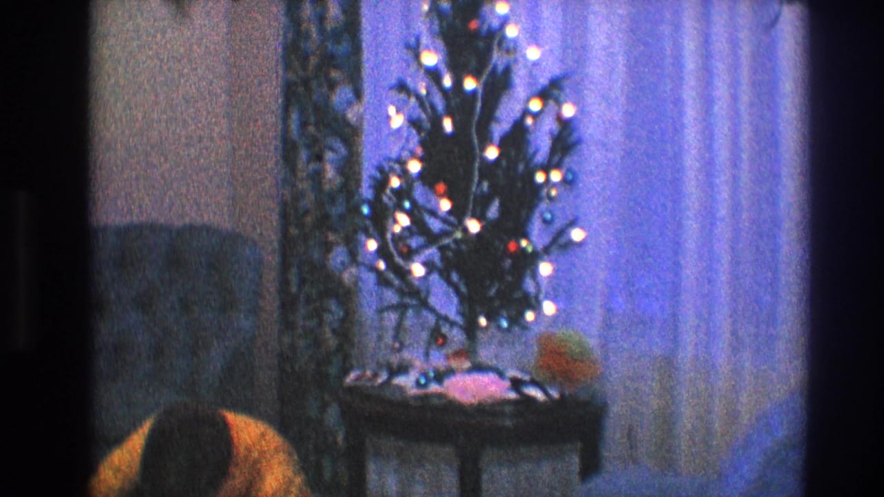 Small lit Christmas tree beside curtains with part of a room visible.