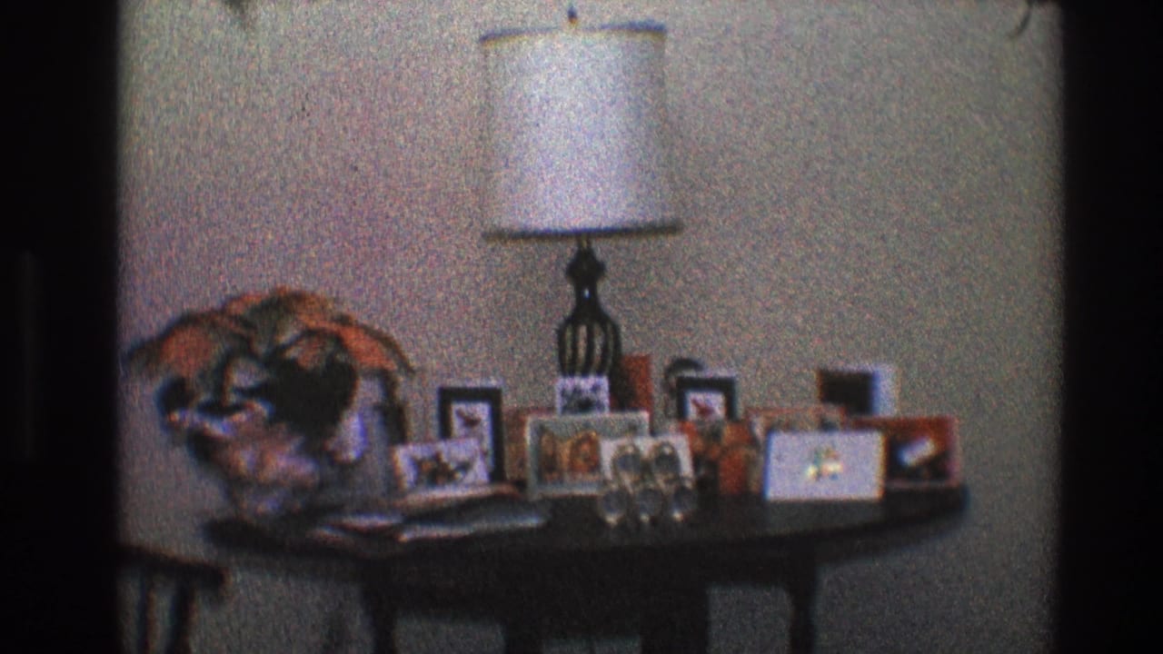 Lamp and framed photos on a table inside a living room.