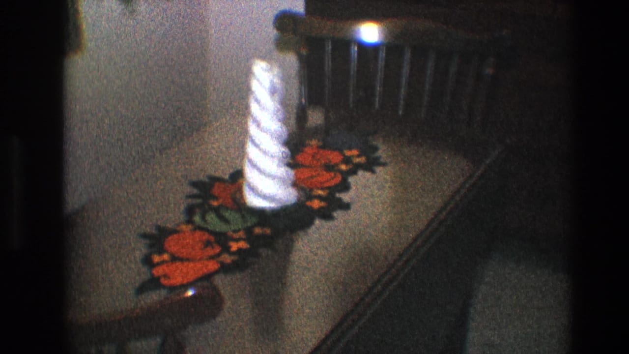 White spiral candle on a red and green runner across a brown table.