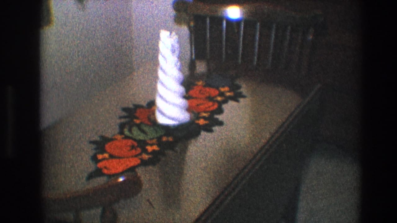 White spiral candle and red runner on a brown table near a dark chair.