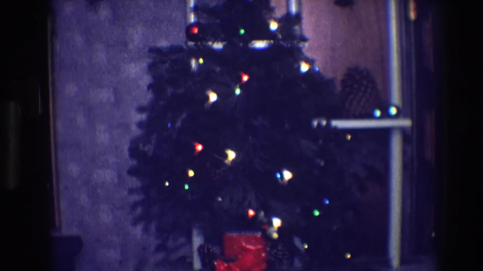 1968 Toledo frame showing a close, soft-focus view of a Christmas tree with colored bulbs and a red wrapped gift at the base.