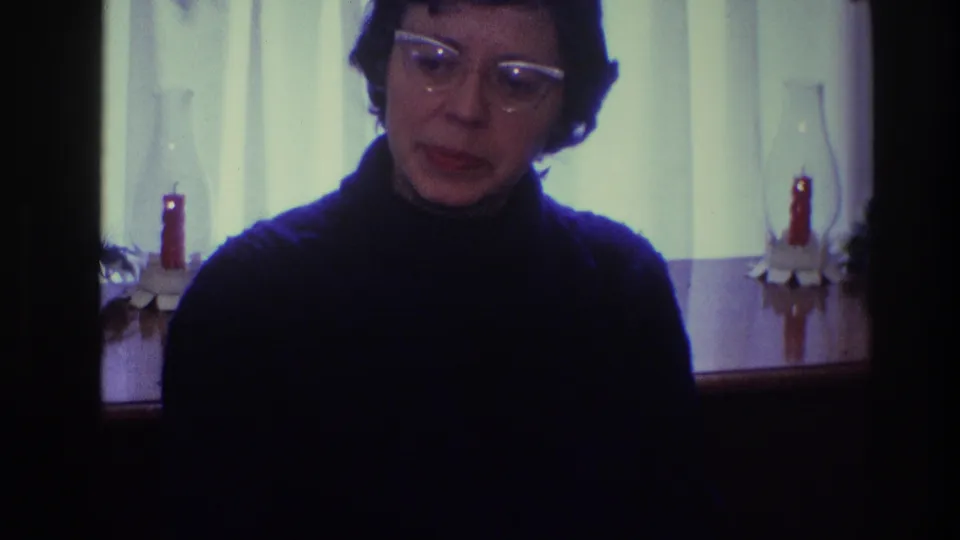 The 1968 Toledo frame shows the woman lowering her gaze, with vintage glasses, dark clothing, curtained window light, and red candles behind her.