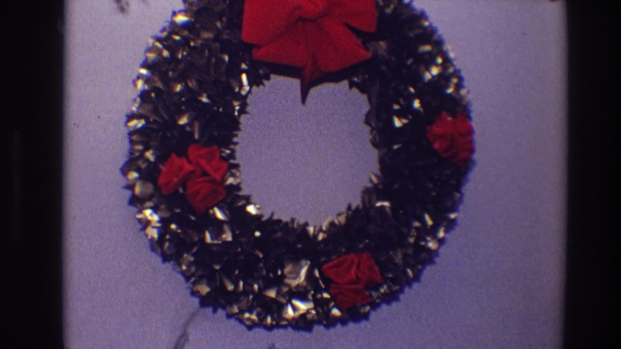 Close view of the same Christmas wreath with red bow and red flowers on an interior wall.
