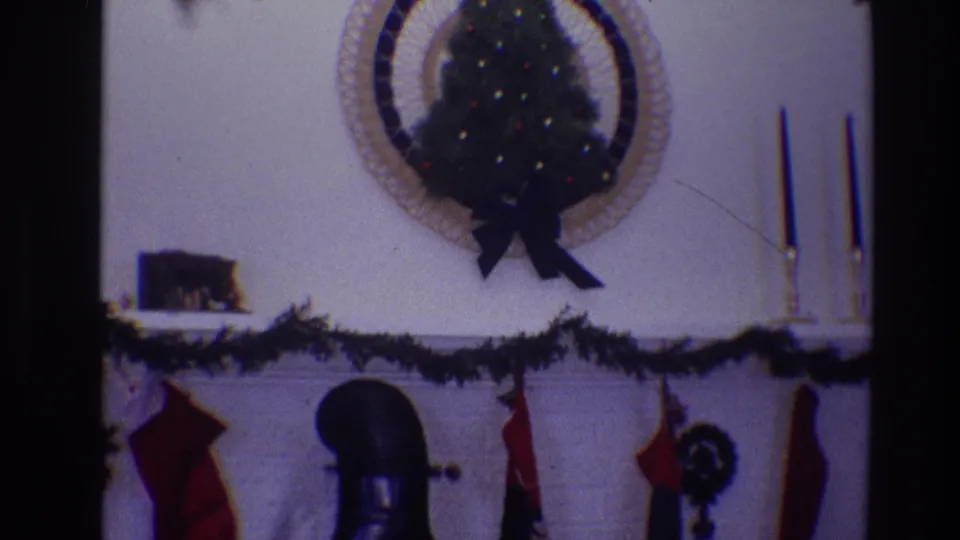 1968 Toledo home interior showing a holiday fireplace mantel with garland, stockings, a small lit tree above, and taper candles to the side.
