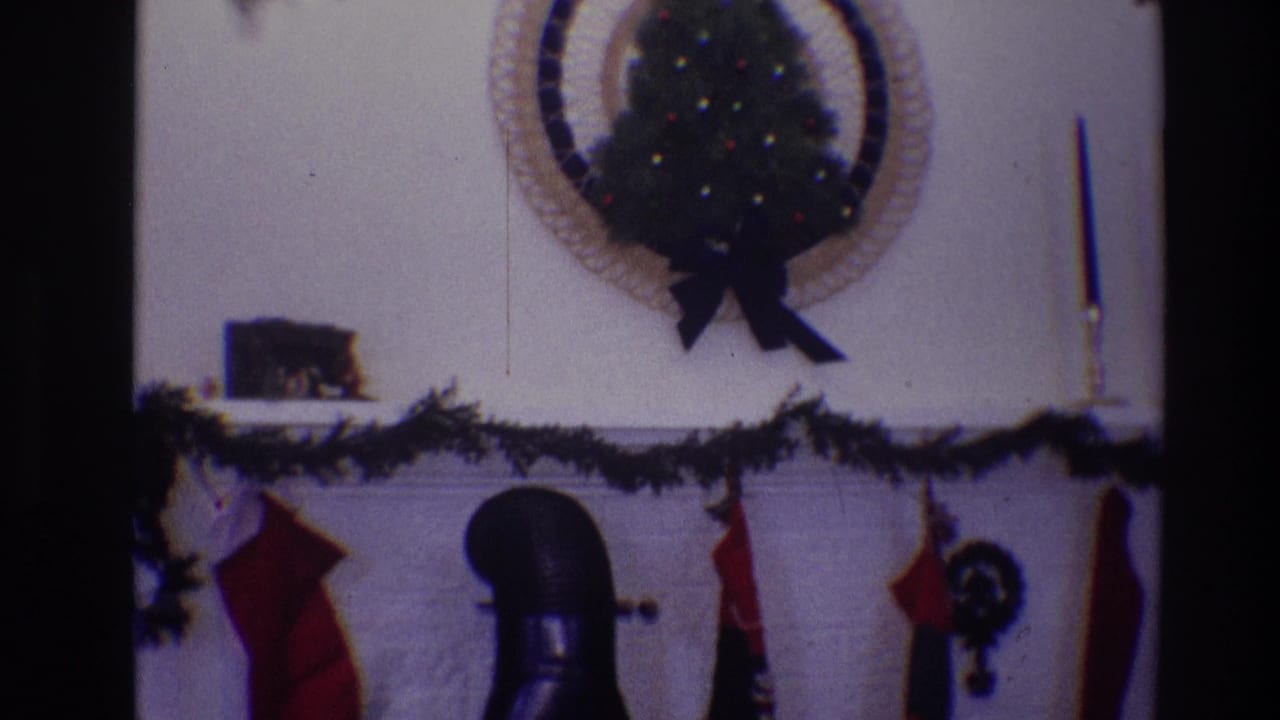 Holiday mantel with red stockings, garland, wall tree, candlestick, and black chimney pipe.
