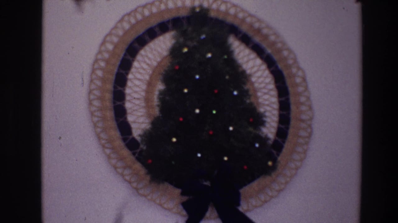 Closer view of a small Christmas tree with colored lights inside a circular woven wall frame.