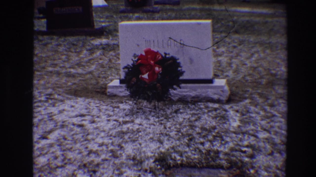 MILLARD grave marker and red-bowed wreath seen across frosty grass.
