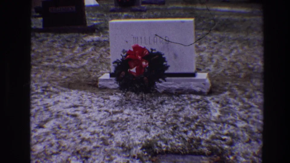 1968 Toledo cemetery view of the MILLARD marker with a wreath and red bow against cold, textured grass.