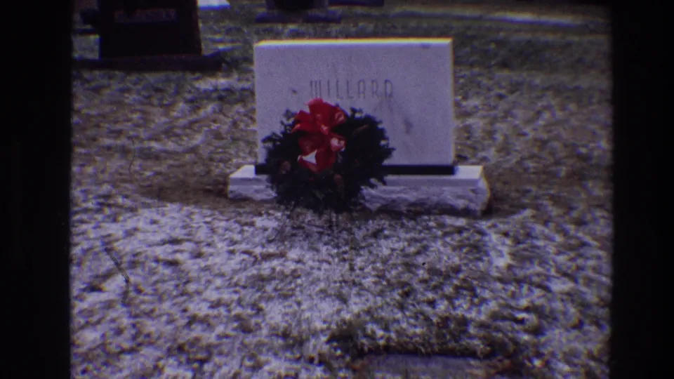 1968 Toledo cemetery frame showing the MILLARD tombstone, seasonal wreath, red bow, and icy ground texture.