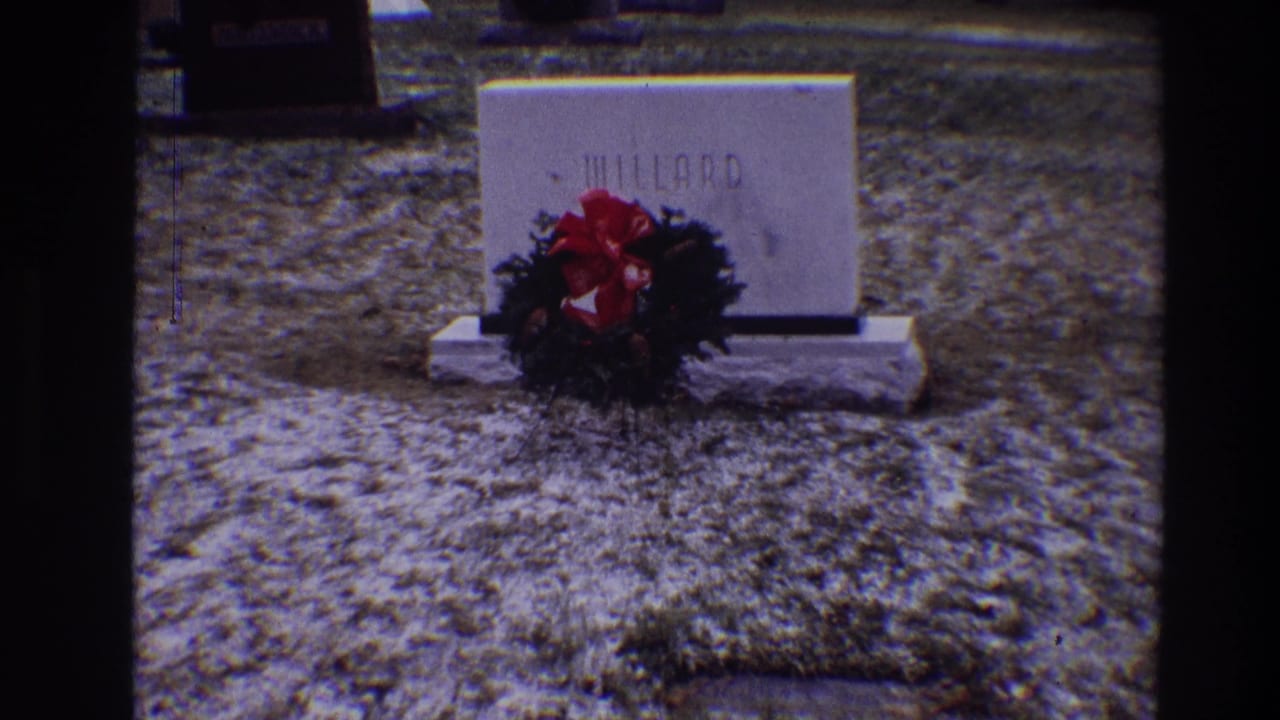 White MILLARD headstone with a wreath and red bow on grass.
