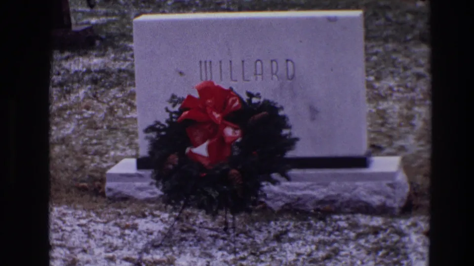 1968 Toledo 8mm frame showing a WILLARD gravestone with an evergreen Christmas wreath and red bow at its base.