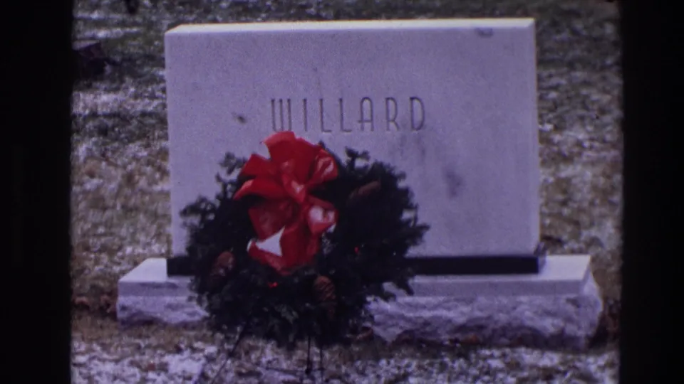 1968 Toledo 8mm frame showing the WILLARD marker with a festive wreath at the base in a quiet cemetery.