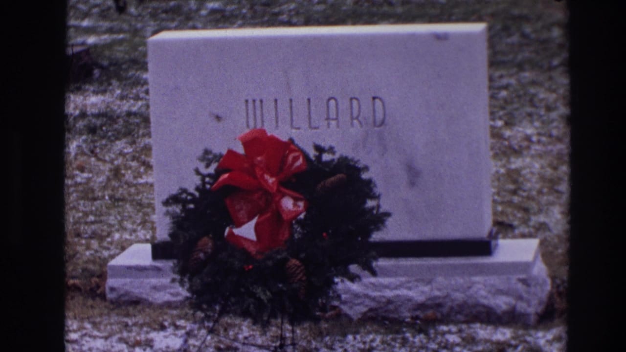 White stone WILLARD gravestone with a Christmas wreath and red bow at its base.