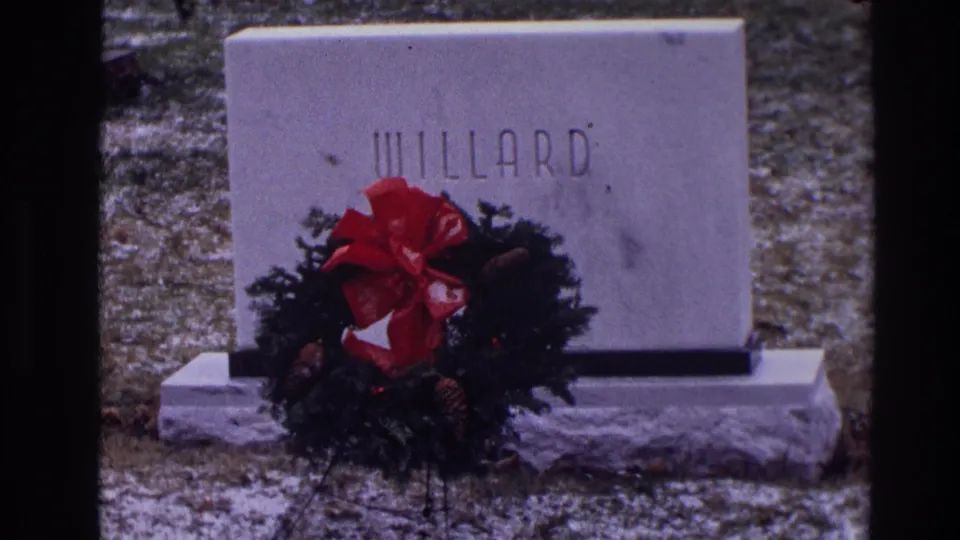 A soft 8mm frame shows the WILLARD gravestone in Toledo, partly covered by a Christmas wreath with a large red bow.