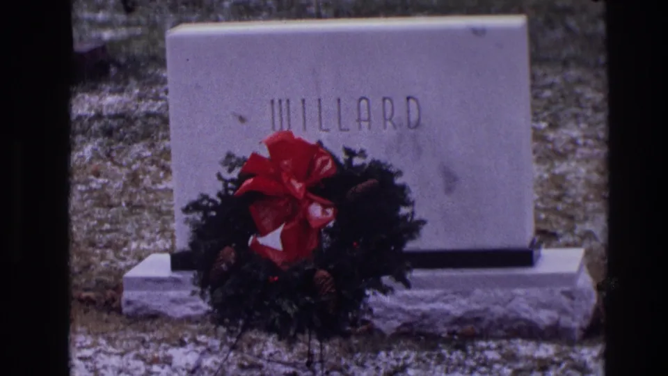 The final frame keeps the WILLARD grave marker and wreath in view, with dark film borders and muted winter color from the 8mm scan.