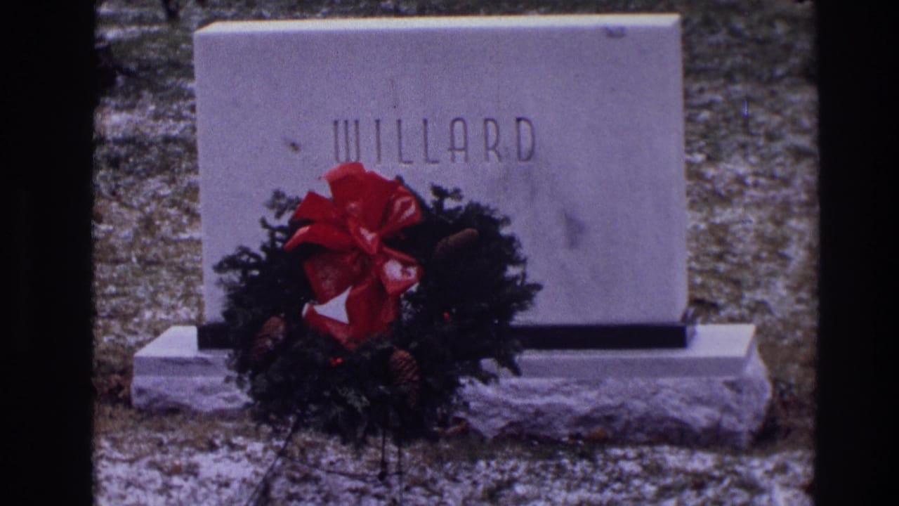 WILLARD grave marker partly covered by a wreath with a red bow.