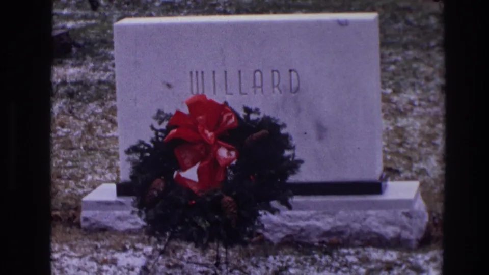 1968 Toledo 8mm shot showing the WILLARD grave marker with a Christmas wreath, pinecones, and light snow around the base.