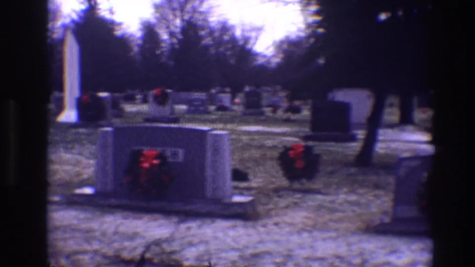 1968 Toledo cemetery panorama with multiple headstones, red wreath decorations, a white monument, bare trees, and winter ground.
