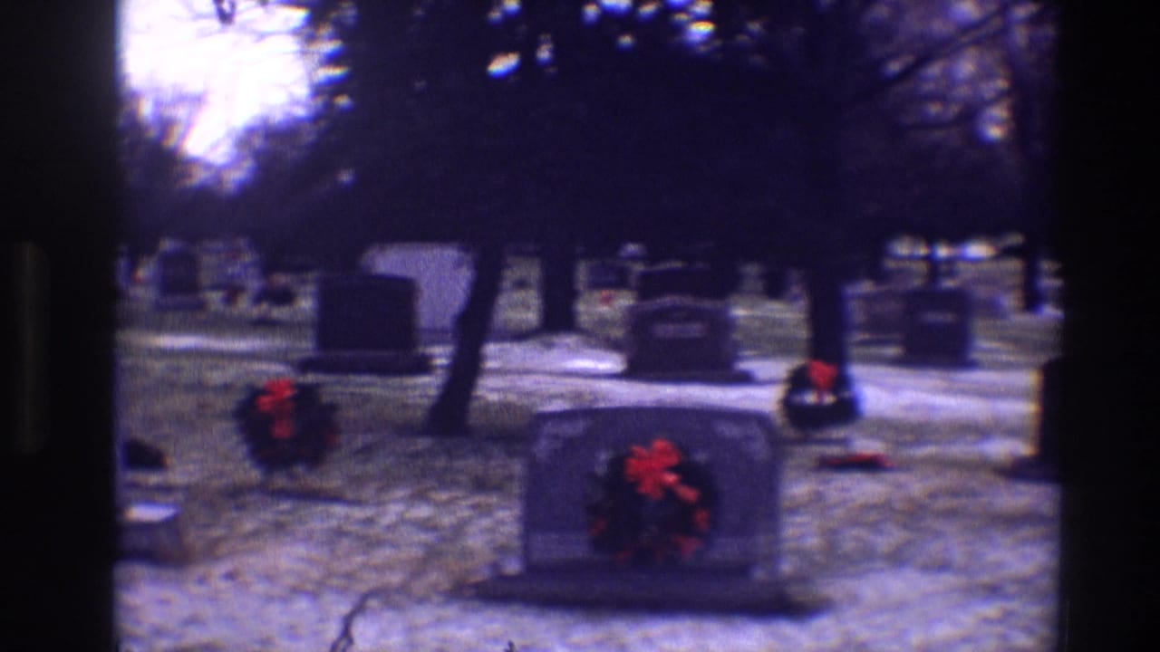 1968 Toledo cemetery view with wreath-marked tombstones, snow-dusted ground, bare trees, and dark 8mm frame edges.