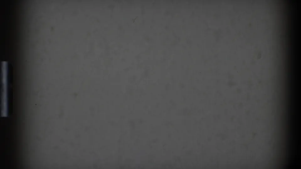 Early frame from the 1968 Toledo 8mm clip showing a gray surface, dark frame borders, and a small vertical light mark before the dinner scene appears.