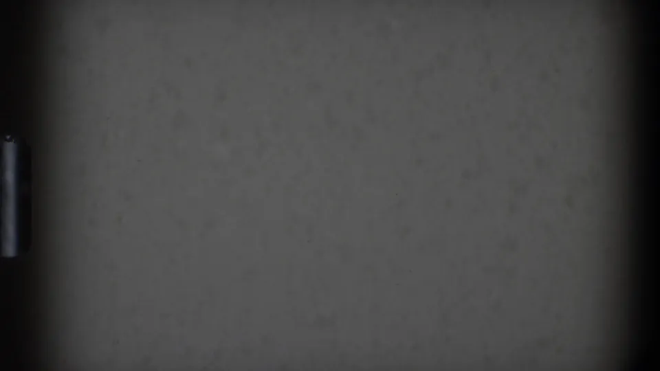 Underexposed 8mm frame from the Toledo home movie showing a gray surface, a central dark vertical band, and a small bright mark.