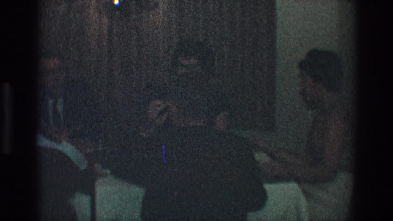 Toledo, Ohio 1968 home-movie frame showing adults in formal dress seated around a dim dining table.