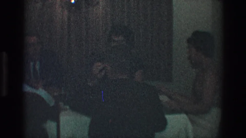 Toledo, Ohio 1968 home-movie frame showing adults in formal dress seated around a dim dining table.