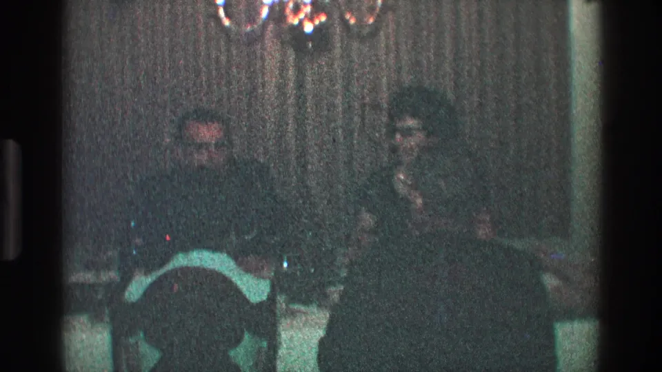 Toledo, Ohio 1968 still showing suited men at a formal dinner table beneath a chandelier.