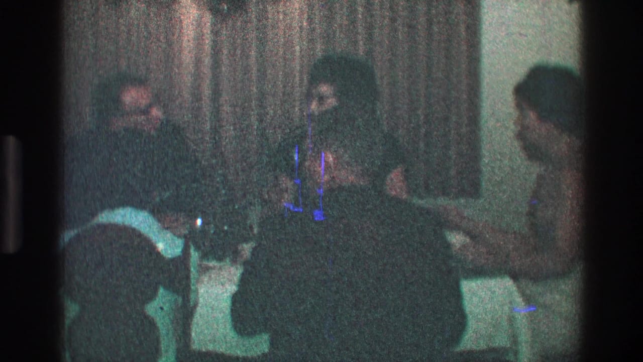 Adults seated around a dim dinner table with curtains behind them.