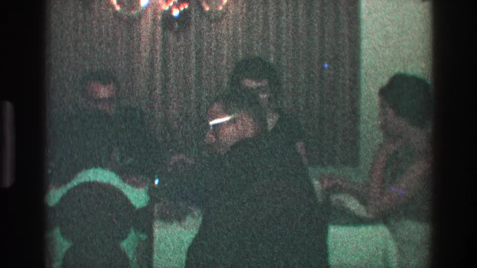 A 1968 Toledo family dinner frame shows a man lifting a cigarette while adults sit around the table.