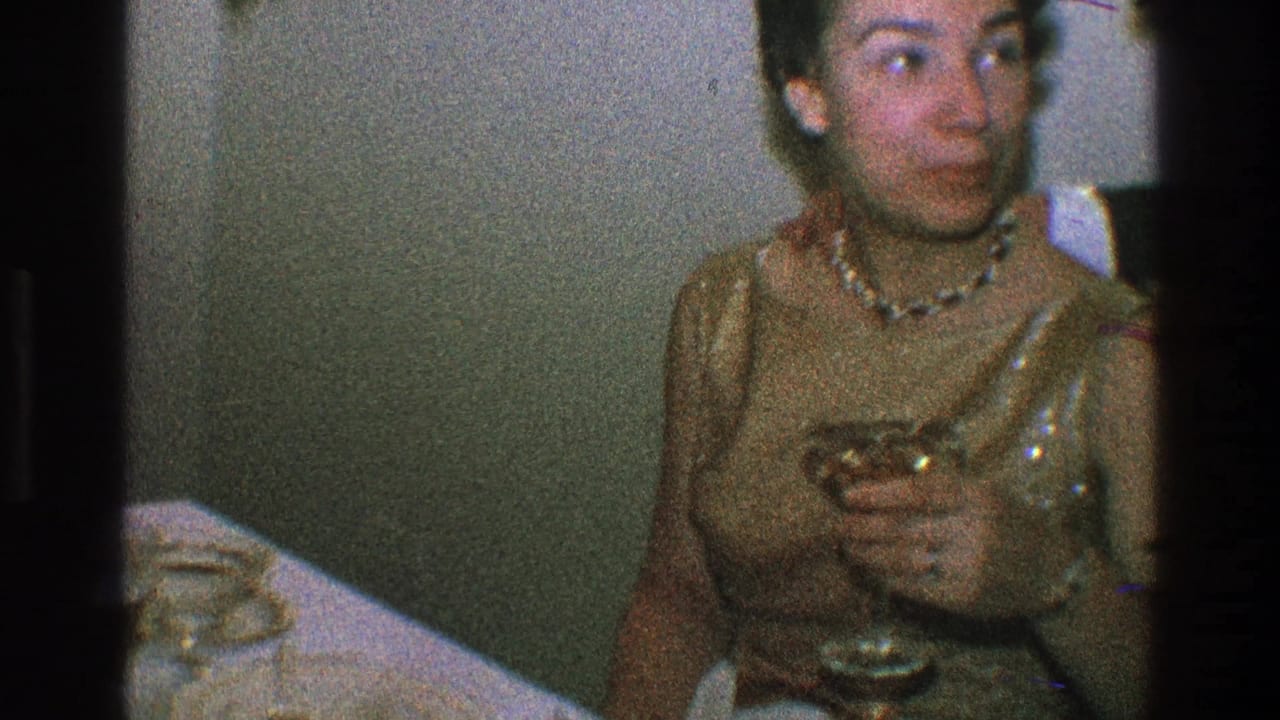 Woman in a gold dress holds a stemmed glass while seated at an indoor table.