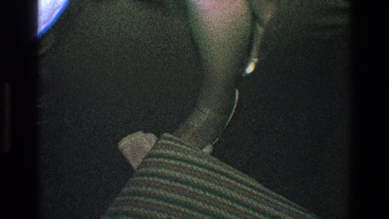 Close view of a person in dark clothing near a striped fabric and pale object.