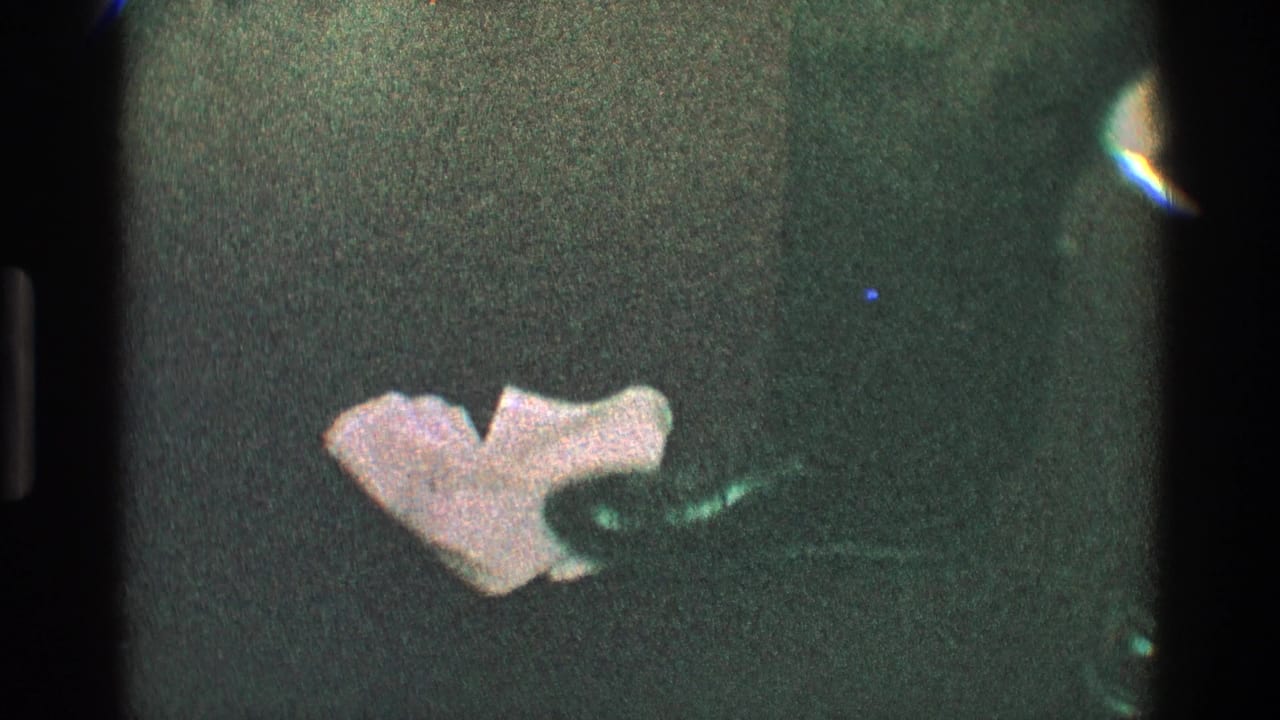 Low view of dark carpet with dancing legs, dark shoes, and a crumpled napkin nearby.