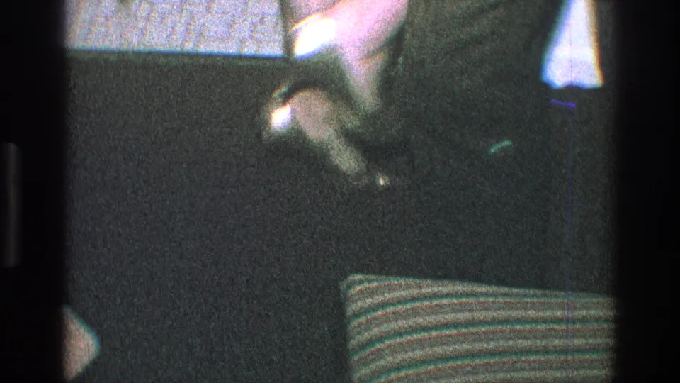 1968 Toledo 8mm frame showing a close, low view of a dancer's shoe and lower leg beside a striped cushion in a dim room.