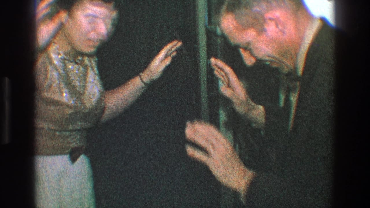 Woman and suited man face each other with raised hands in a dim indoor space.