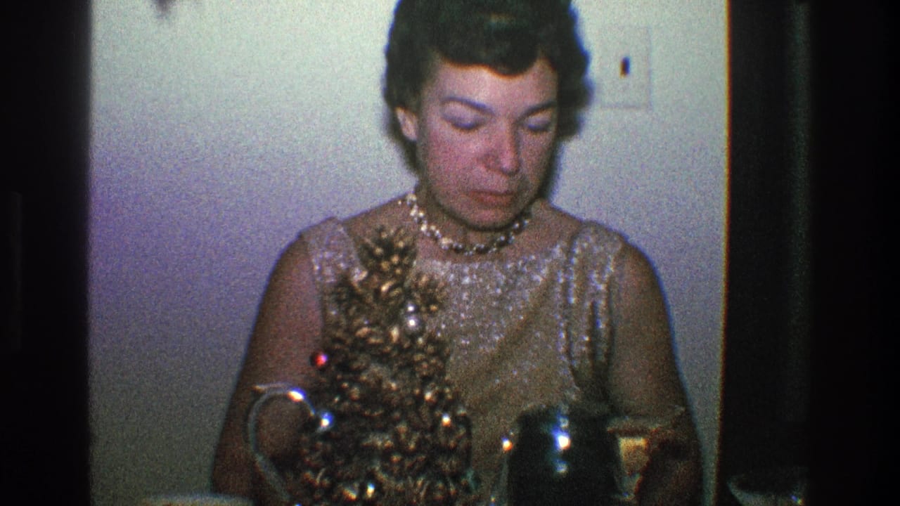 Woman looks downward beside a small decorated Christmas tree on a table.
