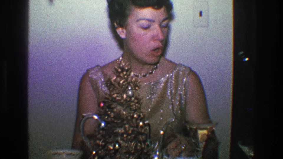 The woman turns to her left with her mouth open, suggesting a candid reaction during the Toledo 1968 holiday home-movie scene.