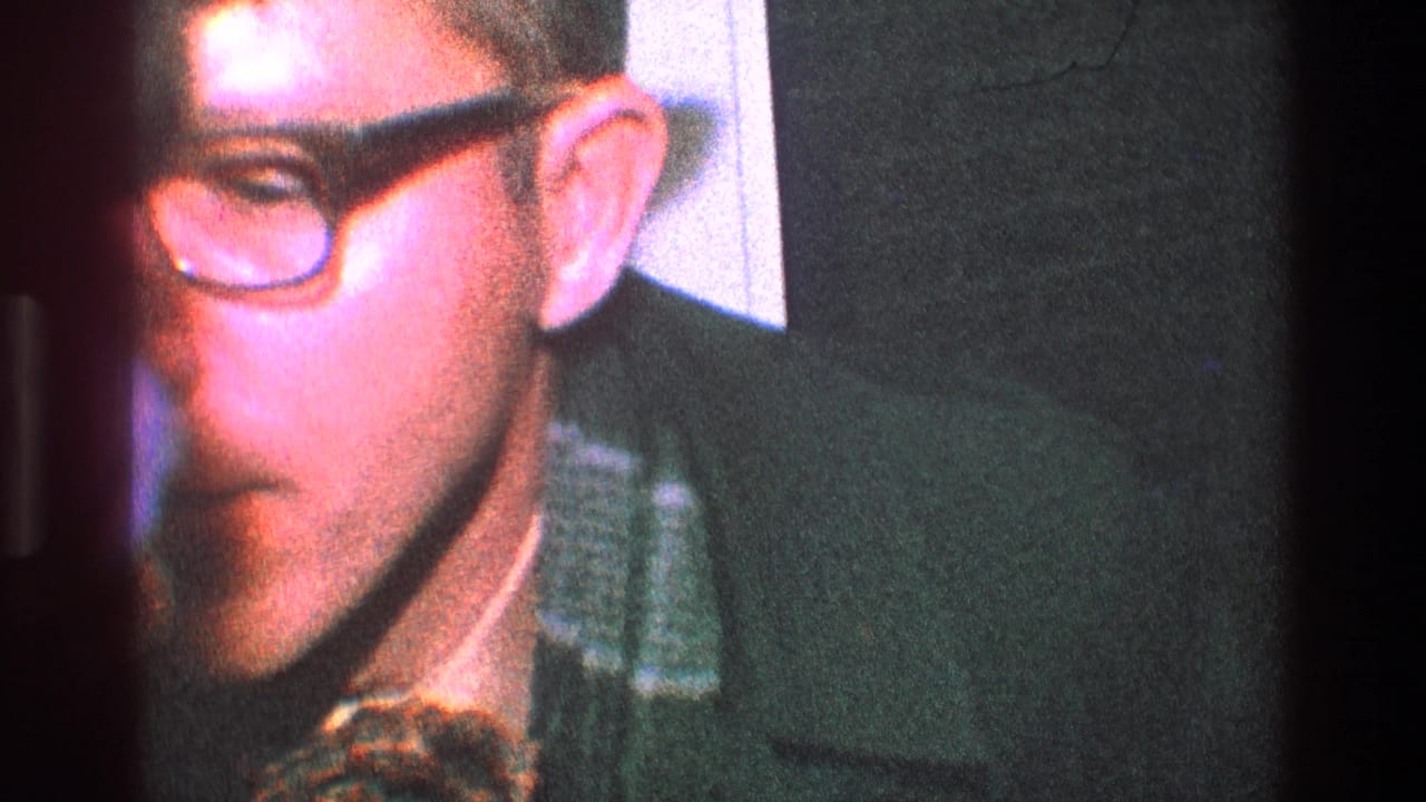 Close view of a man with thick glasses leaning forward indoors.