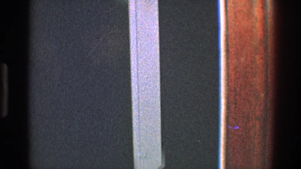 A dim Toledo interior doorway is seen in grainy 8mm footage, with white trim, dark wall areas, and wood-toned vertical surfaces.