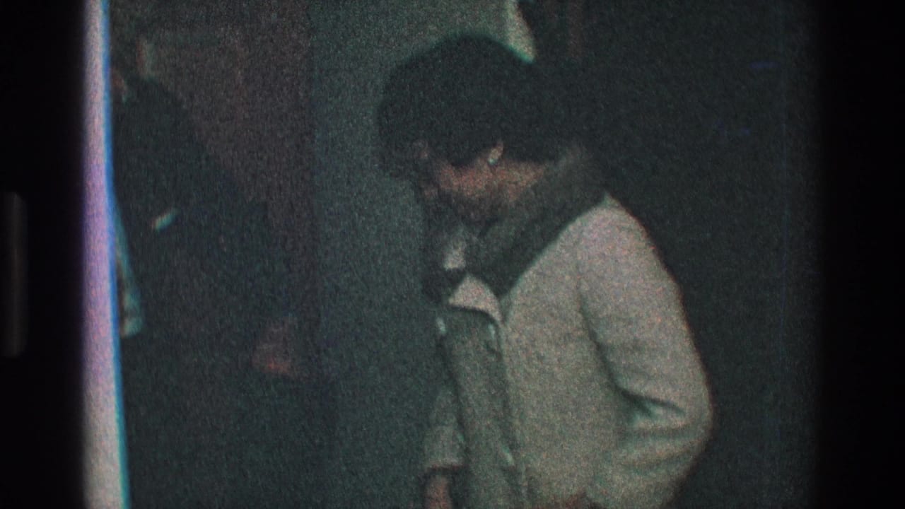 Woman in a light coat bends forward as a man in a dark coat stands close beside her.
