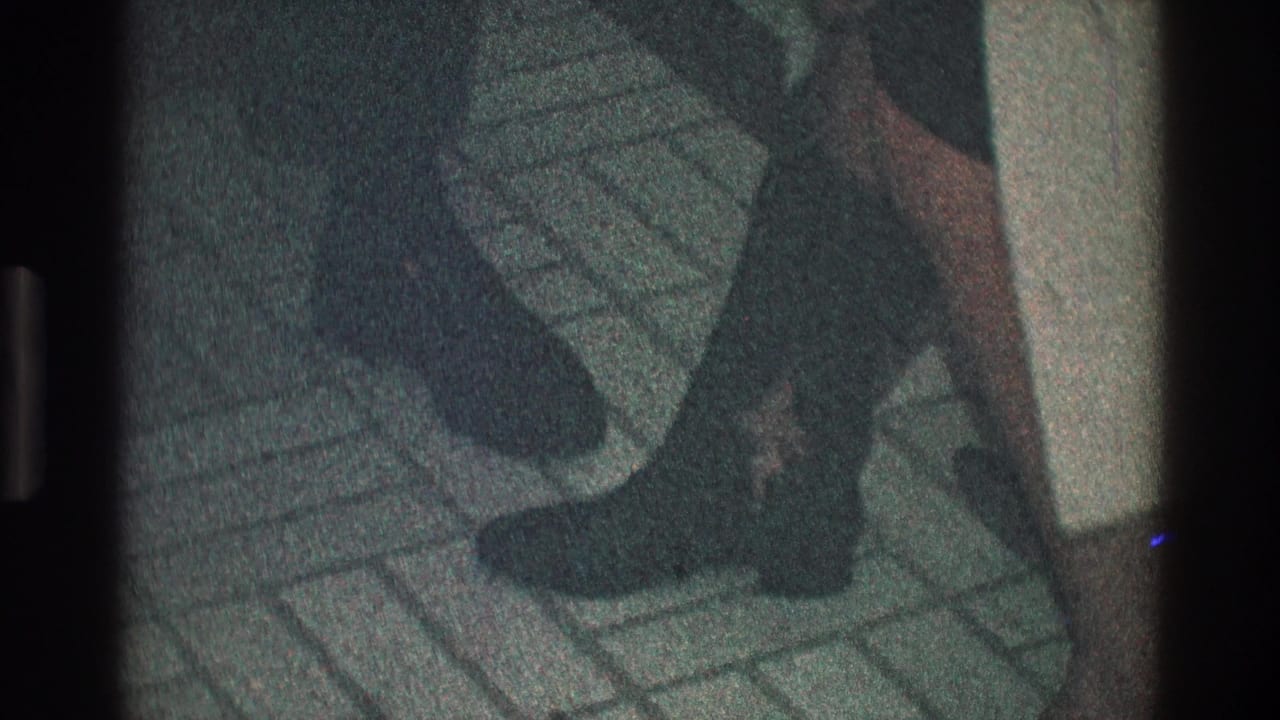 Close view of dark boots and a short skirt on patterned tile flooring.