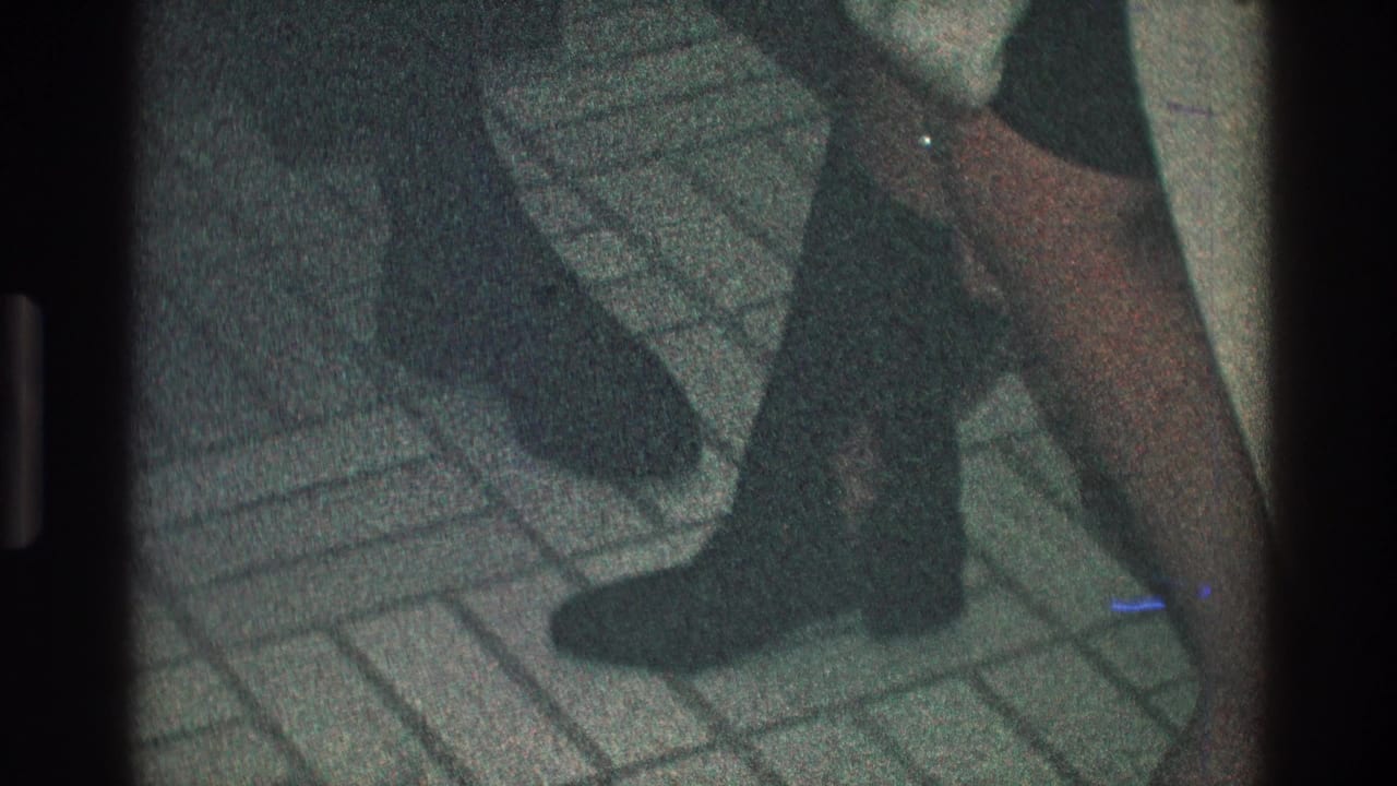 Dark boots and lower legs beside a vertical interior surface.