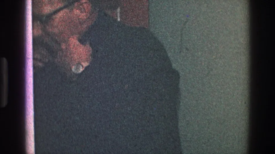 1968 Toledo 8mm frame showing a man in glasses and a dark turtleneck-like top, his hand raised near his mouth.
