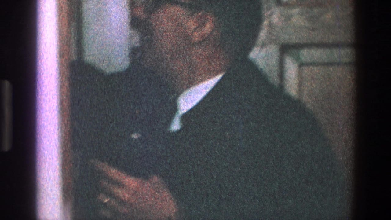 Man in glasses holding his tie near a door or closet.