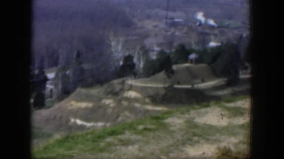 1951 Texas 8mm frame with soft focus on bare trees, small buildings, a road, open land, and a hazy distant backdrop.