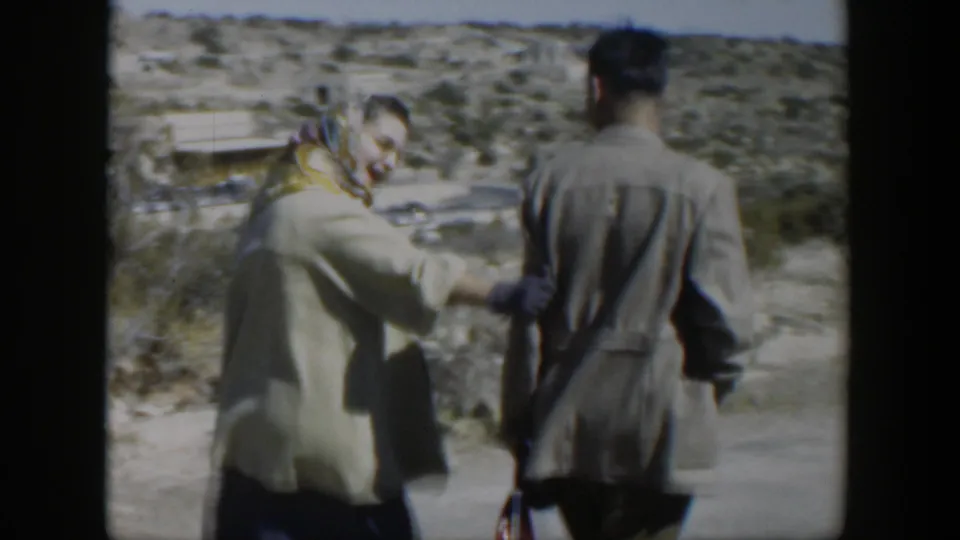 The woman gestures along the road while the man stands with his back to camera in 1951 Texas home-movie footage.