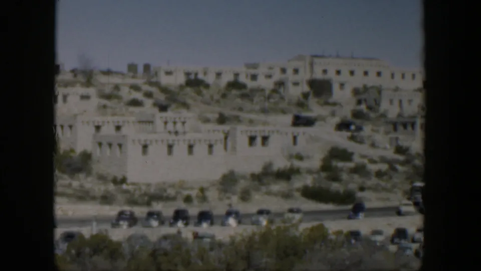 1951 Texas travel footage showing a historic-looking hillside complex with cars along the road below.