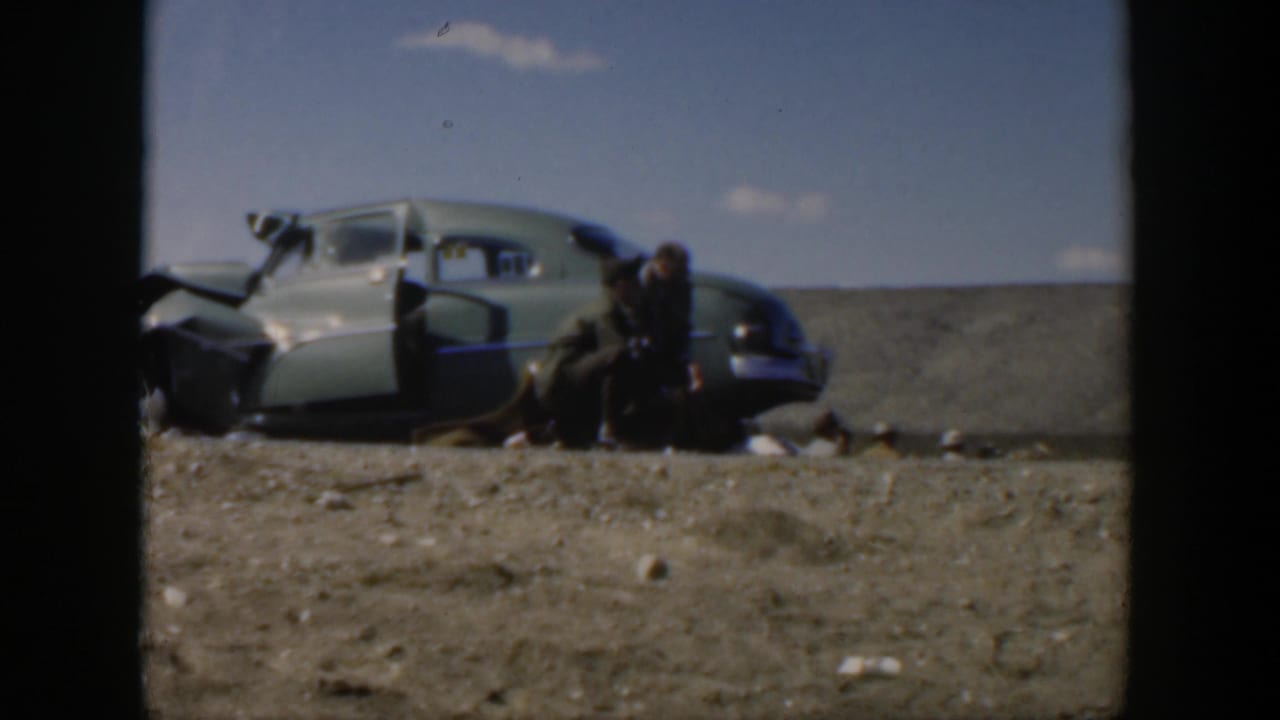 Texas 1951 8mm frame showing a crumpled light-colored car beside a rural road as people stand near the open door.